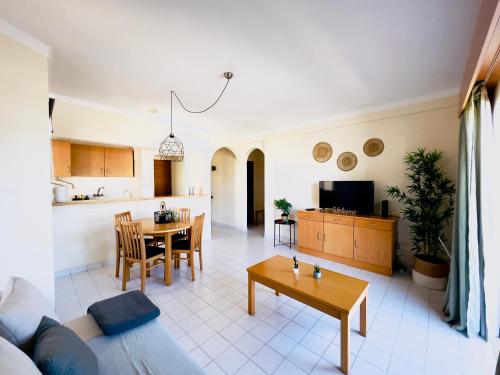 ein Wohnzimmer und eine Küche mit einem Sofa und einem Tisch in der Unterkunft Serenity Homes Casa Aurora Ap T1 in Alvor