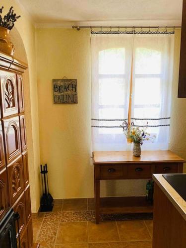 a kitchen with a table and a window with a bench killing sign at Kis Pele nyaraló in Balatongyörök
