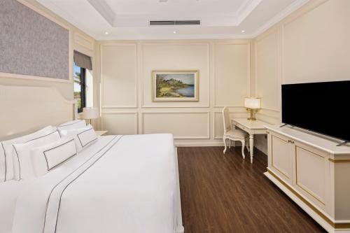 a bedroom with a large white bed and a desk at Vinpearl Cua Hoi, Affiliated by Melia in Cửa Lò