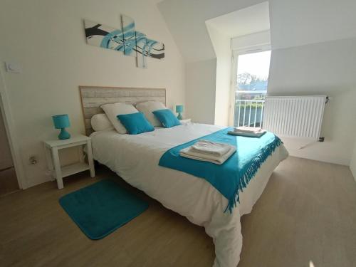 1 dormitorio con 1 cama grande con almohadas azules en Sérénité à la mer, en Concarneau