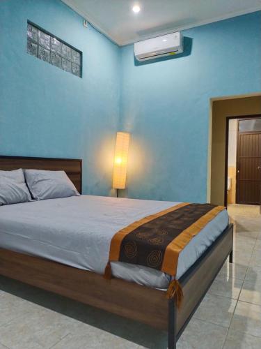 1 dormitorio con cama y pared azul en Loven Sanur Guest House, en Sanur
