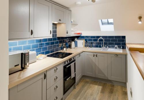 a kitchen with white cabinets and blue tiles at Stroan in New Galloway