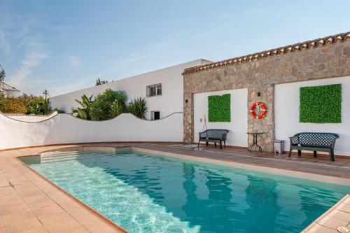 einen Pool mit zwei Stühlen neben einem Haus in der Unterkunft Chalet Fuente4 piscina común famila in Conil de la Frontera