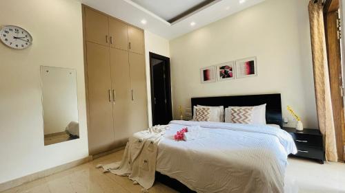 1 dormitorio con 1 cama grande y reloj en la pared en BluO Studio DLF CyberCity - Kitchen, Balcony, Lift en Gurgaon