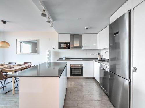 a kitchen with white cabinets and a stainless steel refrigerator at New beach front apartment with large balcony in Torrox Costa