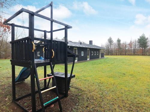 a playground in a field with a house in the background at 6 person holiday home in H jslev in Højslev