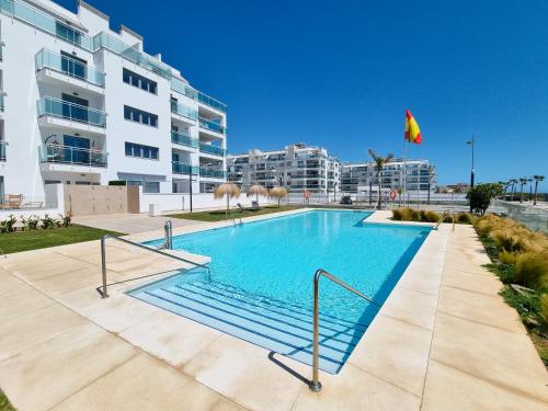 a swimming pool in front of a building at New beach front apartment with large balcony in Torrox Costa