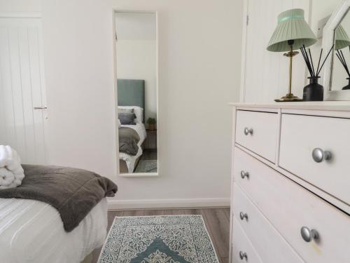 a bedroom with a dresser and a mirror at The Old Coach House in Conwy