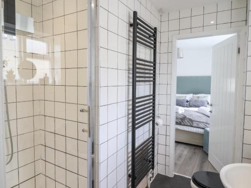 a bathroom with white tiled walls and a mirror at The Old Coach House in Conwy