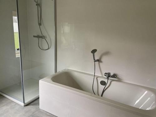 een badkamer met een wit bad en een douche bij Attractive holiday home in Noordwijkerhout with garden in Noordwijkerhout
