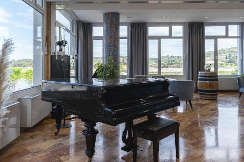 a piano in a living room with windows at Hotel Oleander - Oleander Resort in Strunjan