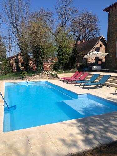 a swimming pool with two lounge chairs and a house at Maison de la Comtesse in Cosne-dʼAllier