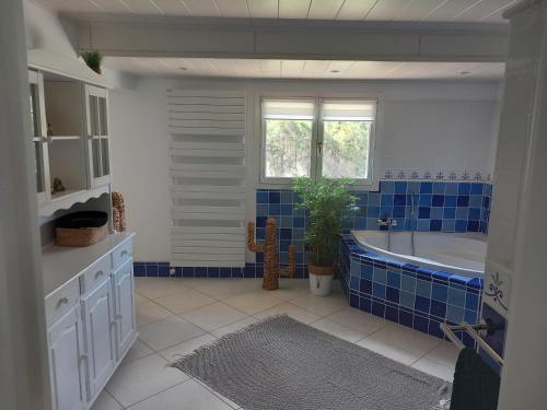 a bathroom with blue tiles and a tub and a window at GÎTE LA MOUNTAGNA in Peyroules