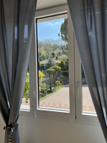 a window with blue curtains and a view of a garden at Cà del Fili in Lenno