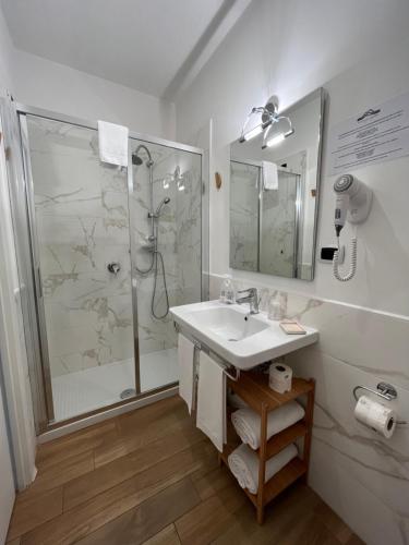 uma casa de banho branca com um chuveiro e um lavatório. em Residenza Madonna em Pompeia