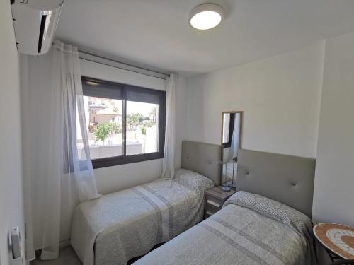1 dormitorio con 2 camas y ventana en Beach house los alcazares, en Los Alcázares