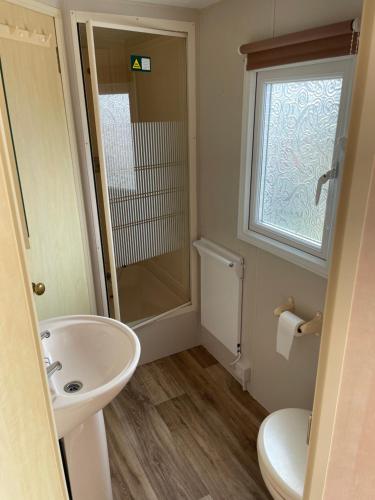uma casa de banho com um lavatório, um WC e uma janela. em Charming 6 birth caravan in skegness em Skegness