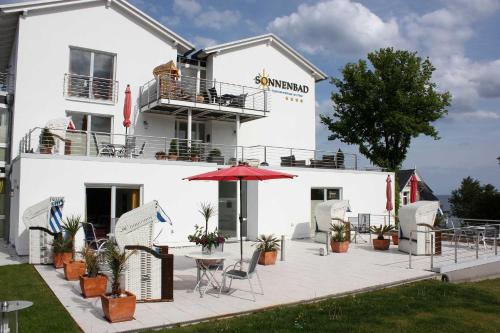 ein weißes Gebäude mit einem Tisch und einem Regenschirm in der Unterkunft Appartement Nr 10 im Sonnenbad in Sassnitz