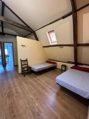 a room with two beds and a chair in it at Albergue de peregrinos Compostela in Molinaseca