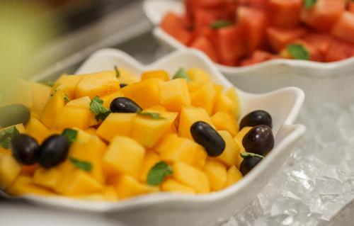 un bol de fruits avec des olives et des mangues noires dans l'établissement Caspia Hotel New Delhi, à New Delhi