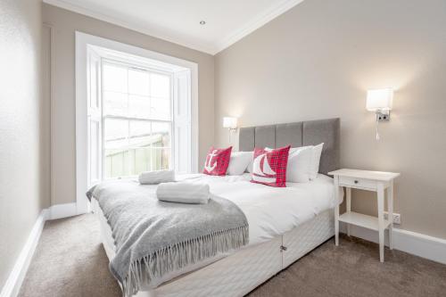 1 dormitorio con 1 cama grande con almohadas rojas y blancas en Market Street Apartment Sleeps 6, en St Andrews