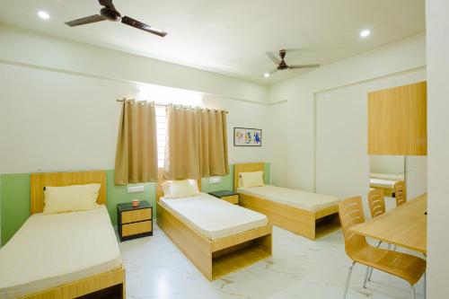 um quarto com 2 camas, uma secretária e uma mesa em Covie Bannergatta 185 em Bangalore