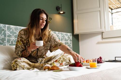 uma mulher sentada numa cama com um prato de comida em Volito Rural Experience em Patù