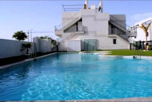 a large swimming pool in front of a building at Modern apartment 250m from the sea with parking space behind gate in Pilar de la Horadada