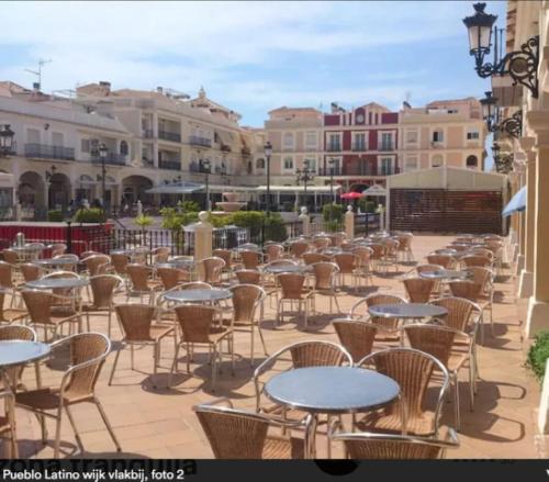 an empty patio with tables and chairs and buildings at Modern apartment 250m from the sea with parking space behind gate in Pilar de la Horadada