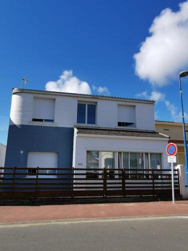 un bâtiment blanc et bleu avec une clôture devant lui dans l'établissement Appartement lumineux 4 personnes, à Saint-Jean-de-Monts