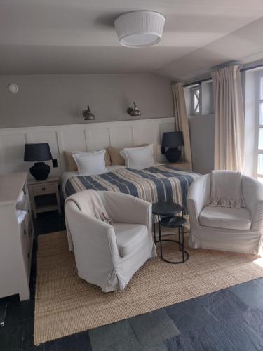 sypialnia z łóżkiem i 2 białymi krzesłami w obiekcie Villa Park Wisełka Spa & Wellness w Wisełce