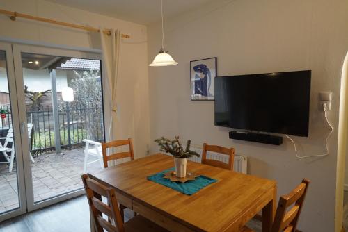 ein Esszimmer mit einem Holztisch und einem Flachbild-TV in der Unterkunft Stylish & Spacious Apartment with Patio in Stams