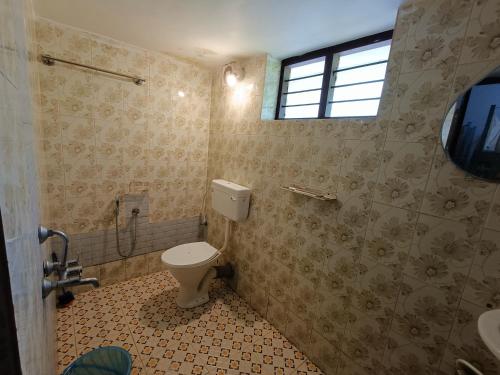 a bathroom with a toilet and a sink and a window at Molly's Hostel in Varkala