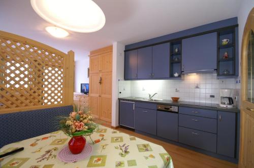 a kitchen with blue cabinets and a vase of flowers on a table at Appartamenti Residence Pars in Badia