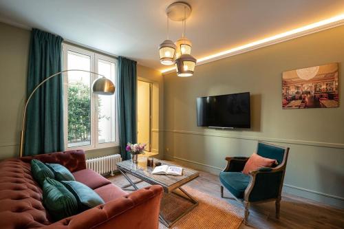 uma sala de estar com um sofá e cadeiras e uma televisão em My Boudoir em Paris