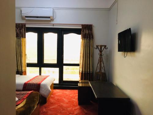 a bedroom with a bed and a large window at Hotell Hill Crown in Nagarkot