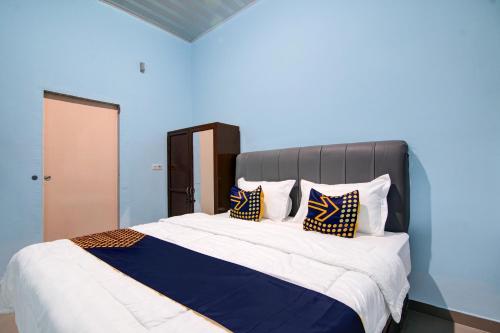 a bedroom with a large bed with blue walls at SPOT ON 92493 Pondok Mulia Syariah in Pekanbaru
