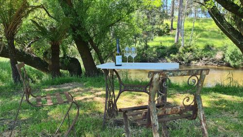 a table with a bottle of wine and two glasses at The Hammock in Moondarra