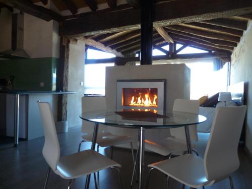 una chimenea en un comedor con mesa y sillas en Suite rural con jacuzzi en Cabañas de Polendos