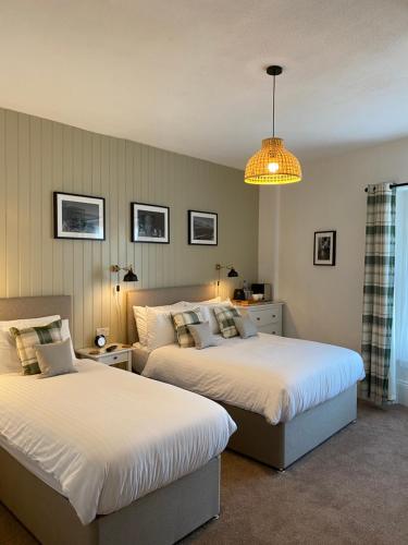 1 dormitorio con 2 camas y lámpara de araña en Glenthorne Guest House, en Tenby
