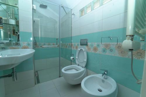 La salle de bains est pourvue de toilettes et d'un lavabo. dans l'établissement Olimpic Hotel, à Tirana