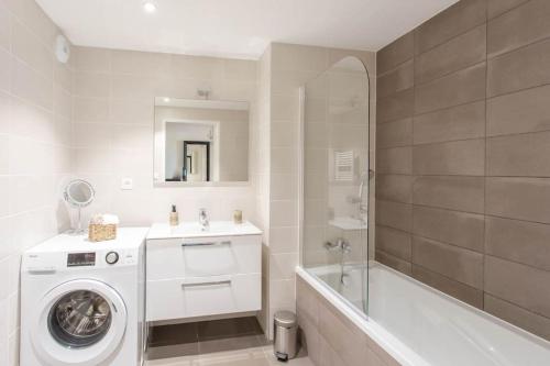 La salle de bains blanche est pourvue d'un lave-linge et d'une baignoire. dans l'établissement A7- 2 BDR Sea & Mountain View - AC, Parking, Pool & Terrace, à Antibes