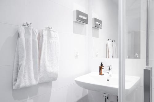 Baño blanco con lavabo y espejo en Hotel Østerport, en Copenhague