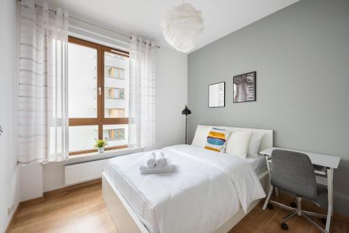 ワルシャワにあるObrzeżna Comfort Apartmentの白いベッドルーム(ベッド1台、デスク、窓付)