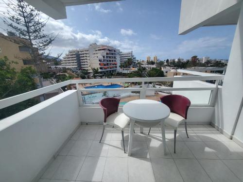 a white table and chairs on a balcony with a view at Cozy Apartment near the beach in Playa de las Americas