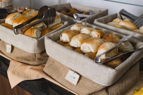three baskets of breads and other pastries on display at Al Mare Hotel in Florianópolis