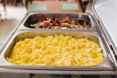 a tray of scrambled eggs and other food on a counter at Al Mare Hotel in Florianópolis