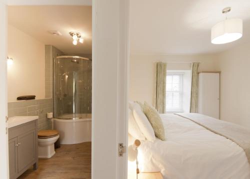 a white bedroom with a bed and a bathroom at Skerrow in New Galloway