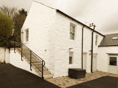 a white brick building with a staircase on it at Skerrow in New Galloway