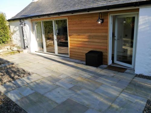 a patio in front of a house with sliding glass doors at Skerrow in New Galloway